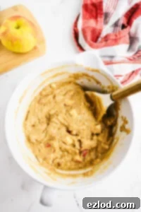 Chopped apples mixed with dry muffin ingredients in a bowl.