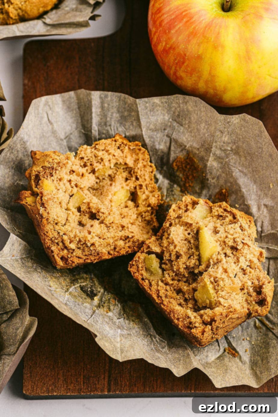 Close up photo of apple muffin, cut in half, laying on parchment liner.