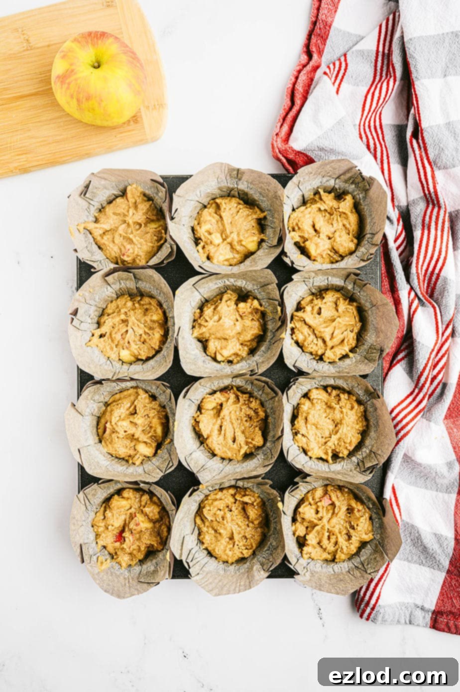 Overhead image: muffin tin full of apple muffin batter, ready for the oven