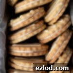 Close up of vegan lemon sandwich cookies stacked in a loaf tin.