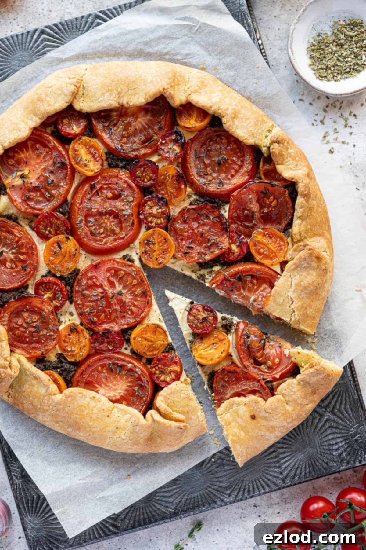 A slice of vegan tomato ricotta galette removed from the whole, revealing the creamy almond cheese, vibrant tomatoes, and golden, crisp cornmeal crust.
