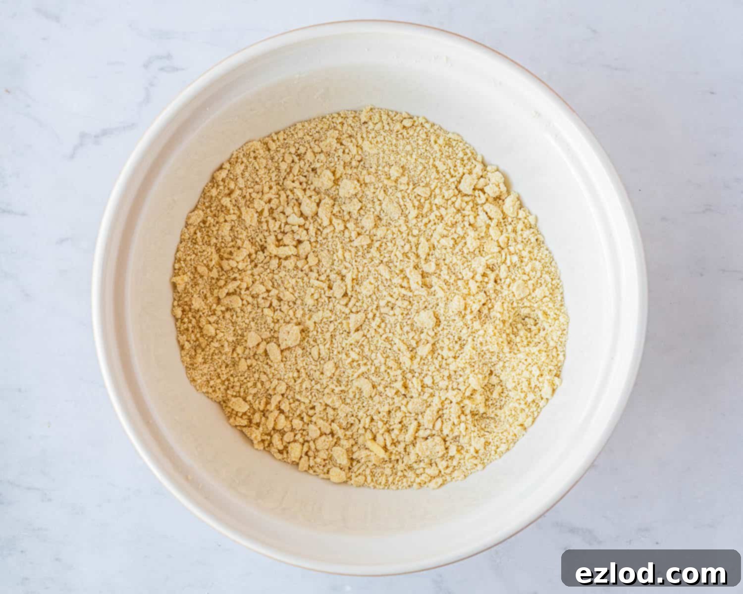 Close-up of the vegan butter being rubbed into the flour and cornmeal mixture, creating a breadcrumb-like texture.