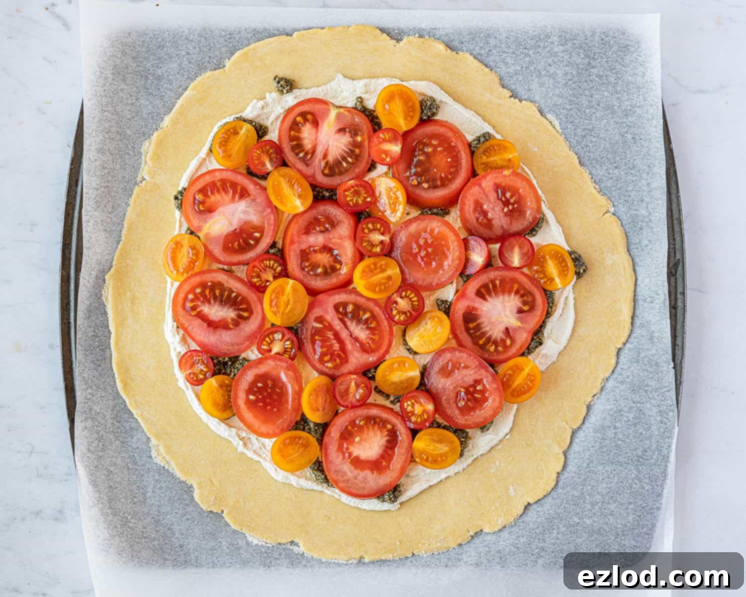 The galette filling, showing the almond cheese dotted with pesto and beautifully arranged fresh tomatoes.