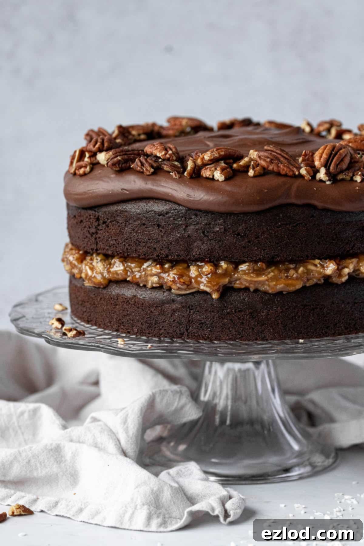 Close up of vegan German chocolate cake on a glass cake stand.