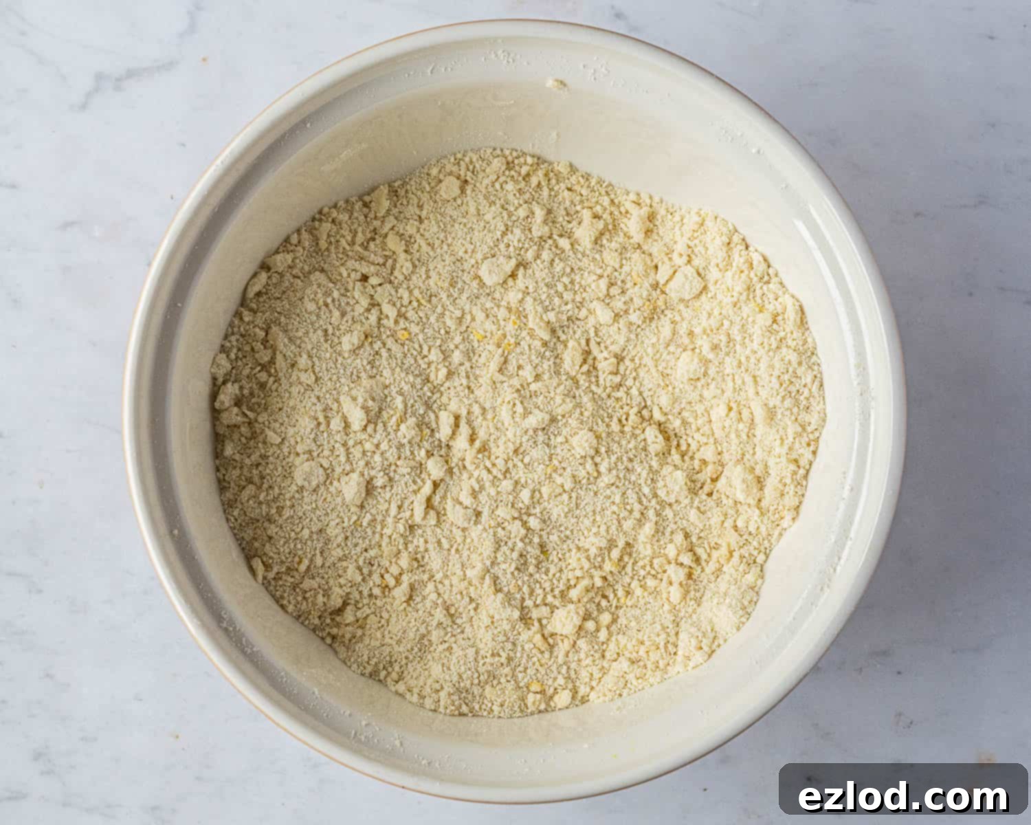 The initial stage of making vegan crostata pastry, showing flour and cold cubed vegan butter rubbed together until it resembles fine breadcrumbs in a large mixing bowl, ready for liquid.