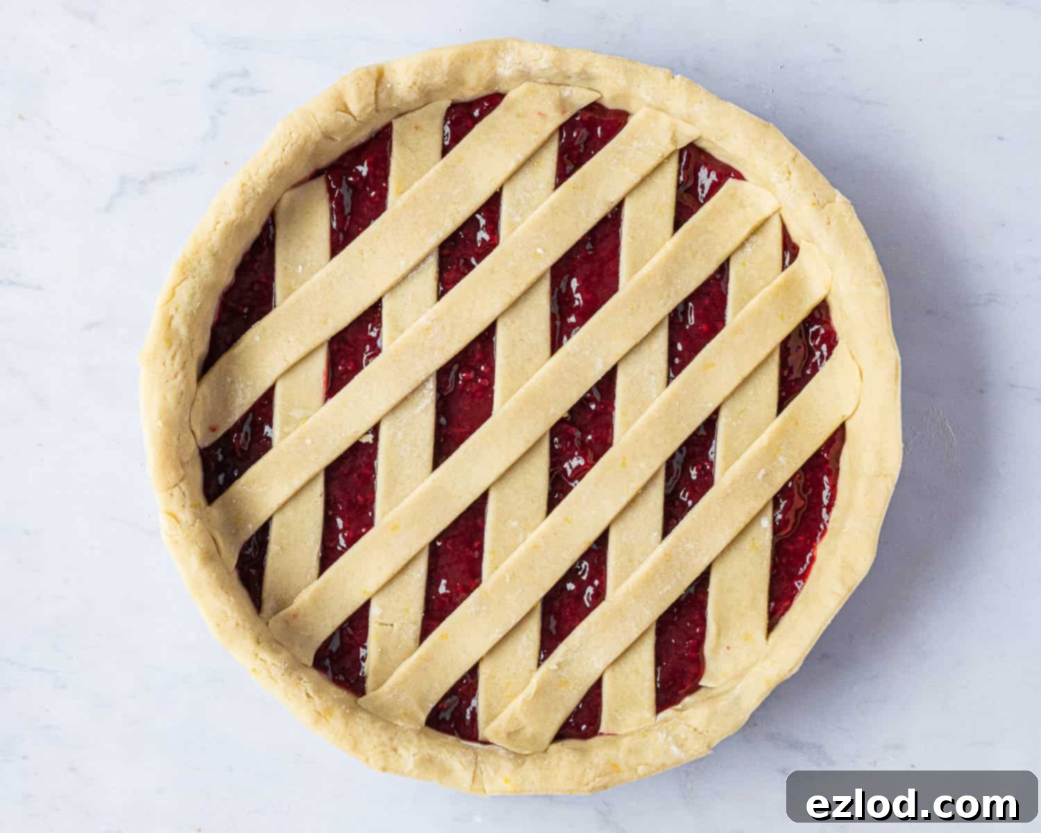 The completed and intricately woven lattice pattern on top of the vegan jam crostata, with all pastry strips perfectly interlocked over the fruit filling.