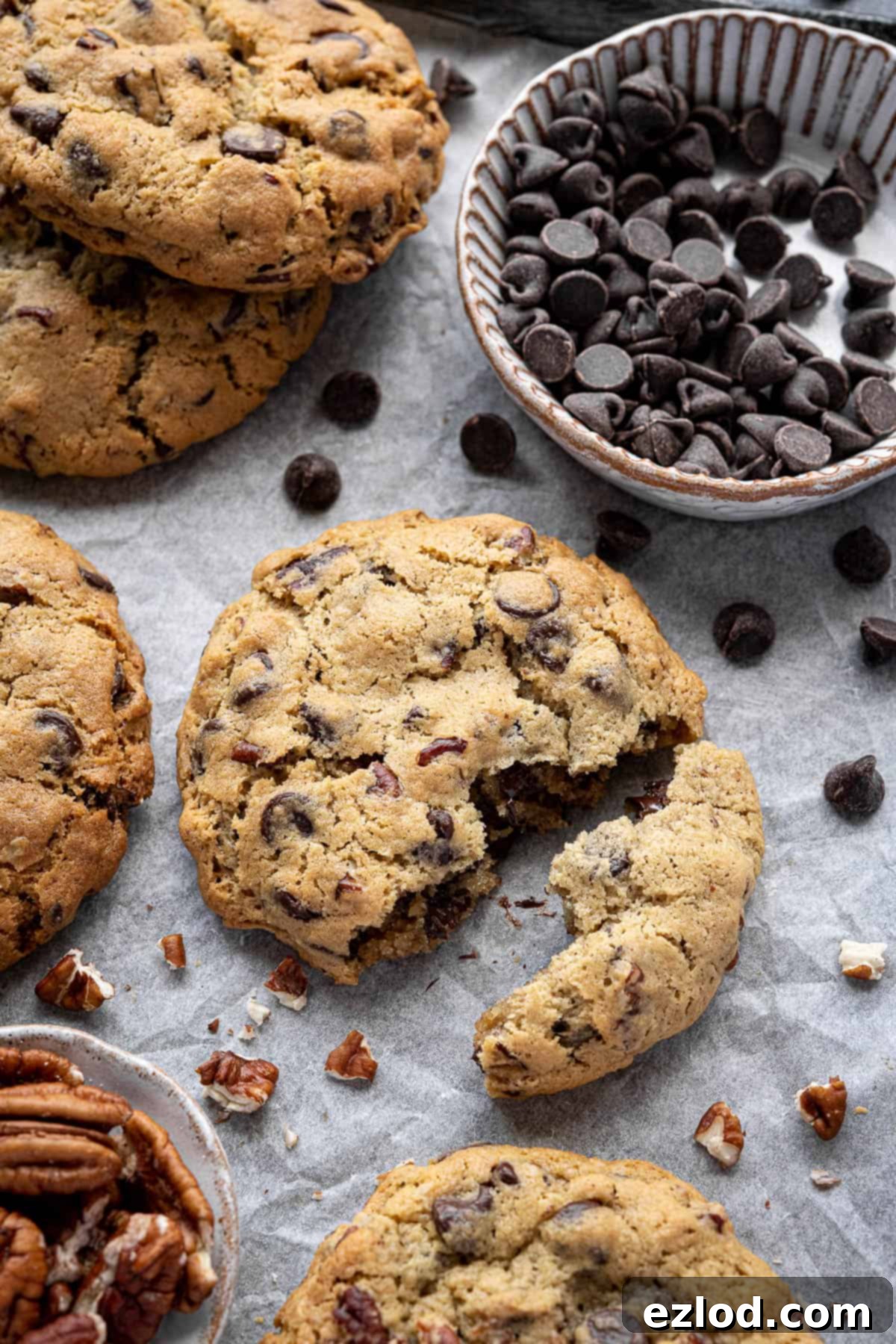 Close up of a chunky chocolate pecan cookie broken in half, revealing gooey chocolate and pecans.