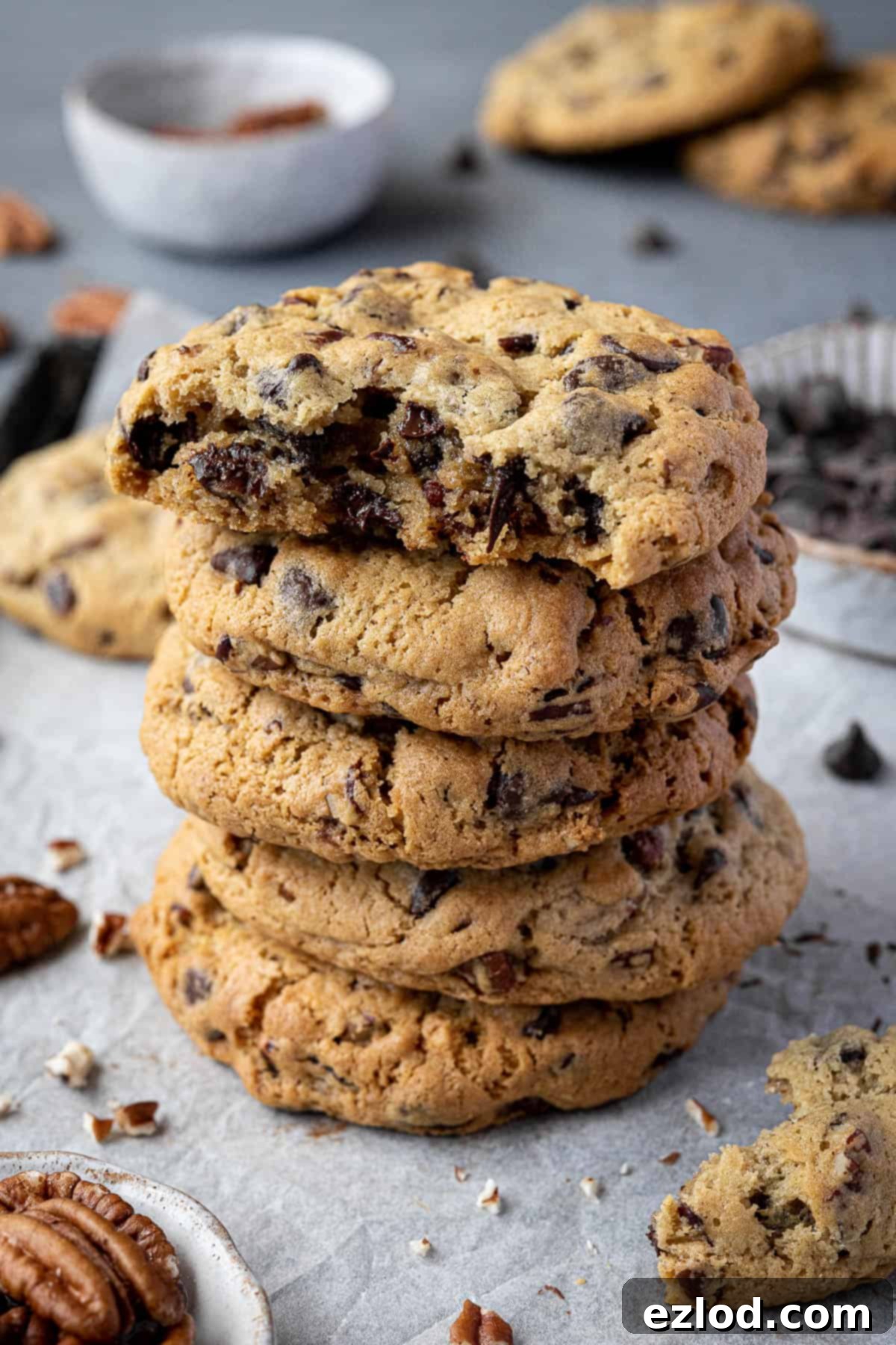 A stack of golden brown chunky chocolate pecan cookies, showcasing their thickness.