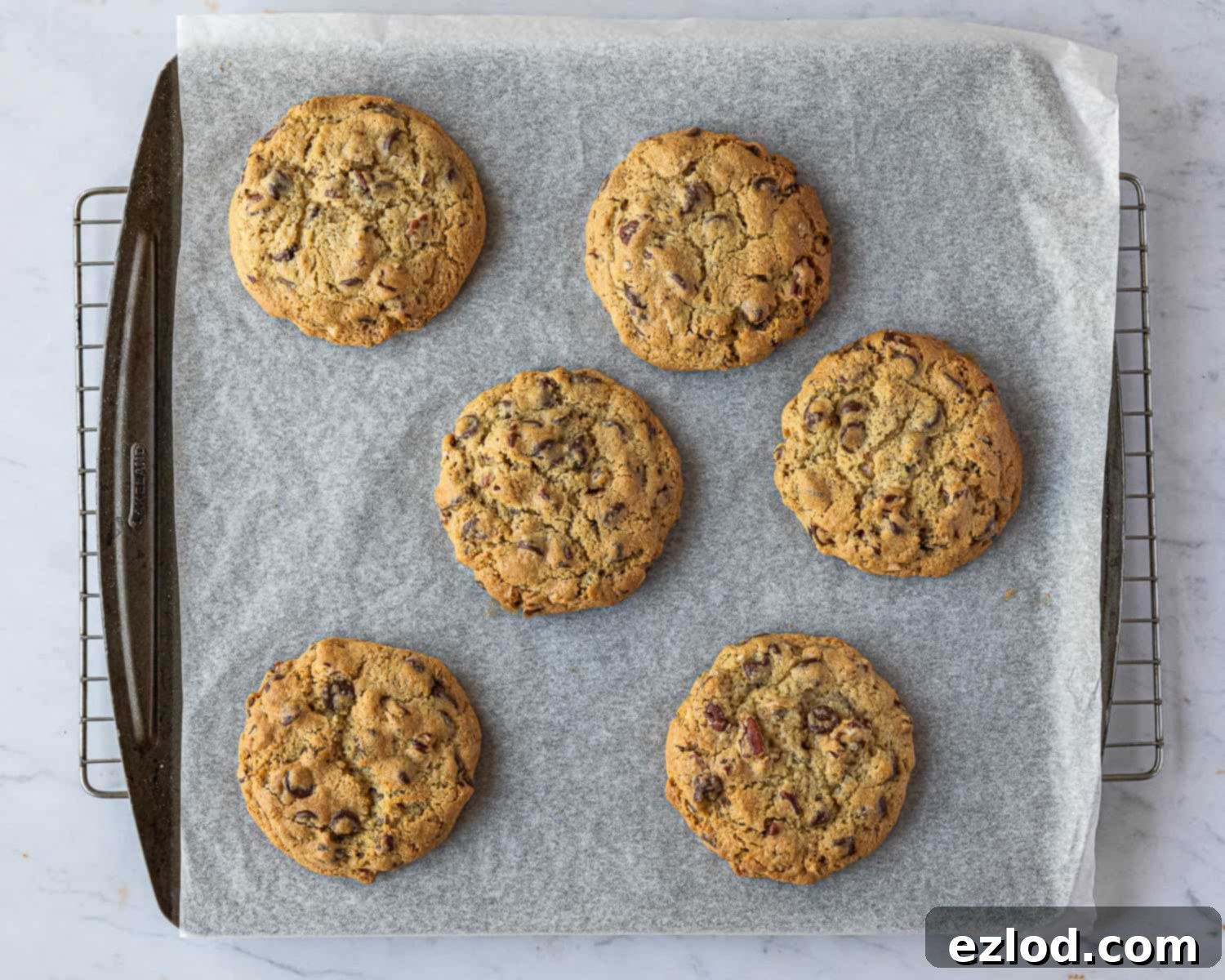 Step 5: Freshly baked chunky chocolate pecan cookies cooling on a baking sheet, golden brown and perfectly risen.
