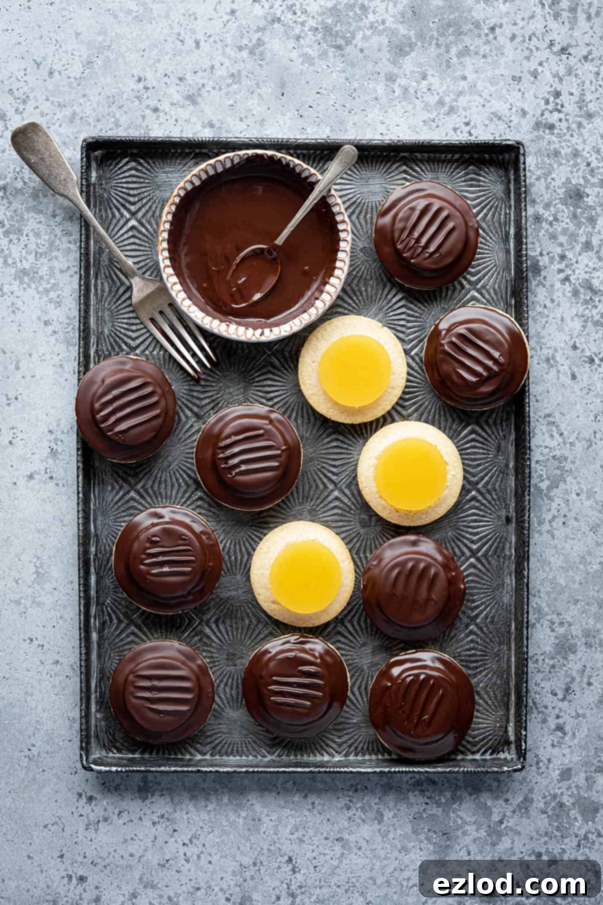 Vegan jaffa cakes on a tray with a bowl of chocolate and a fork.