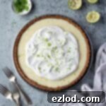 Tangy Vegan Key Lime Pie 13 Vegan key lime pie on a grey surface wiith lime halves, a bowl of lime zest and a pile of forks.