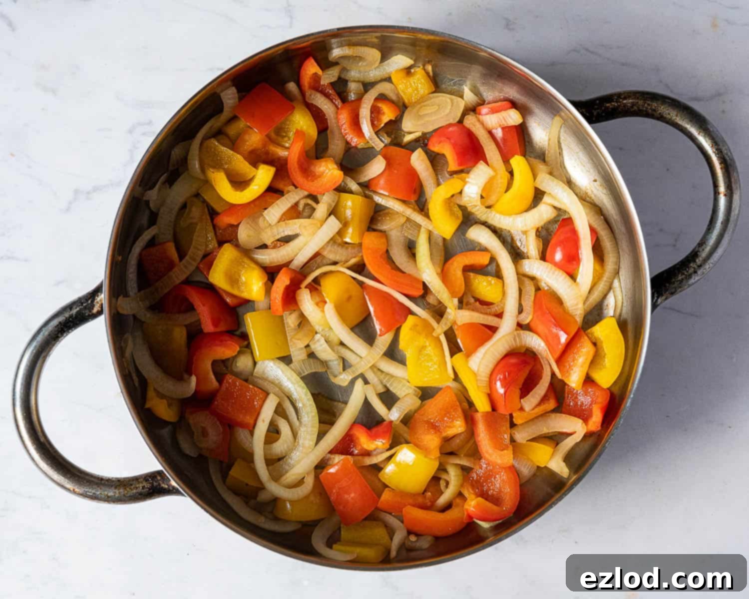 Step 4: Colorful bell peppers and sliced onions being stir-fried in a large pan, softened but still crisp.