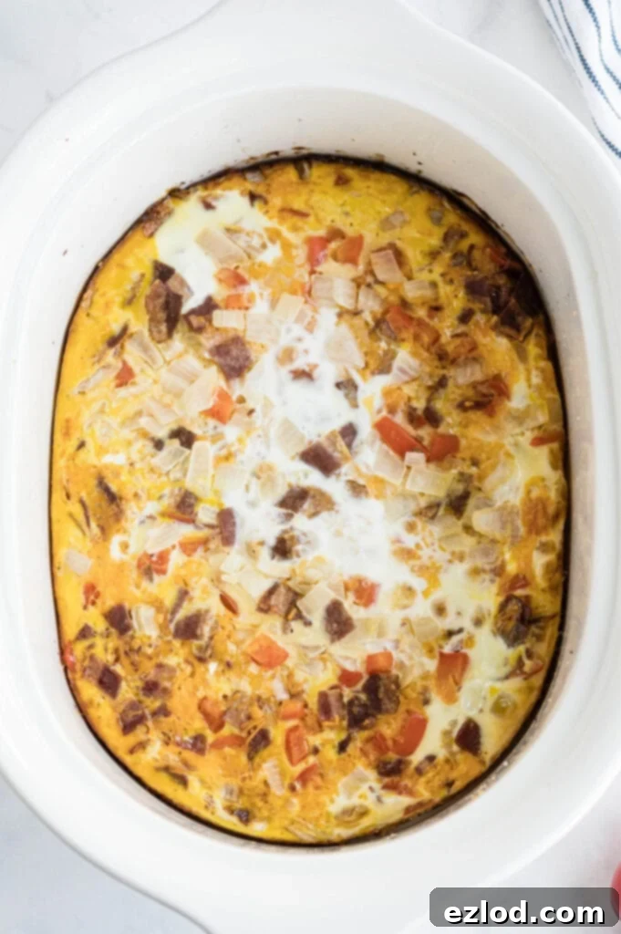 An overhead shot of a crock pot egg casserole with turkey bacon, cheese, and vegetables