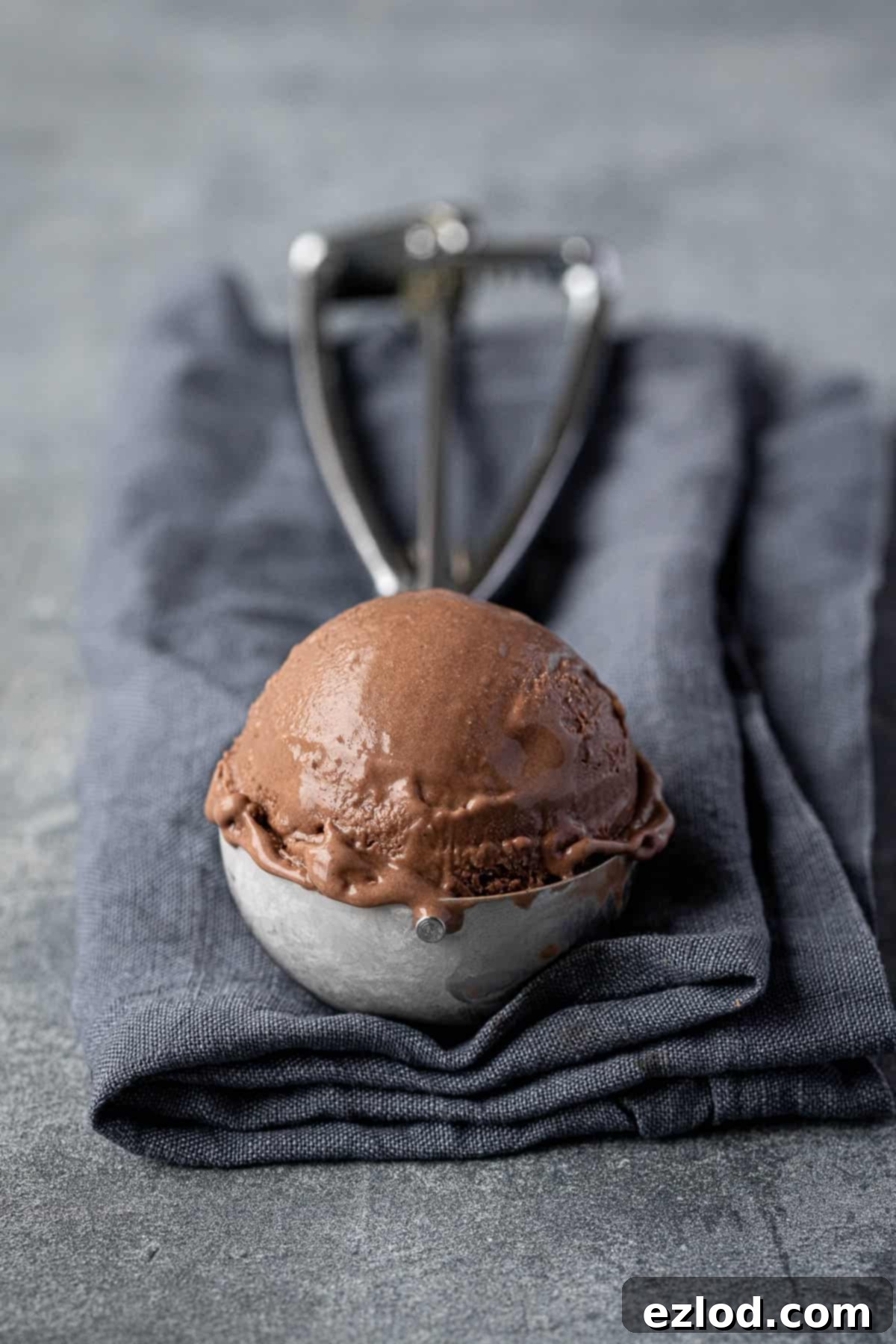 An ice cream scoop loaded with a generous scoop of the creamy vegan malted chocolate ice cream, ready to be served.