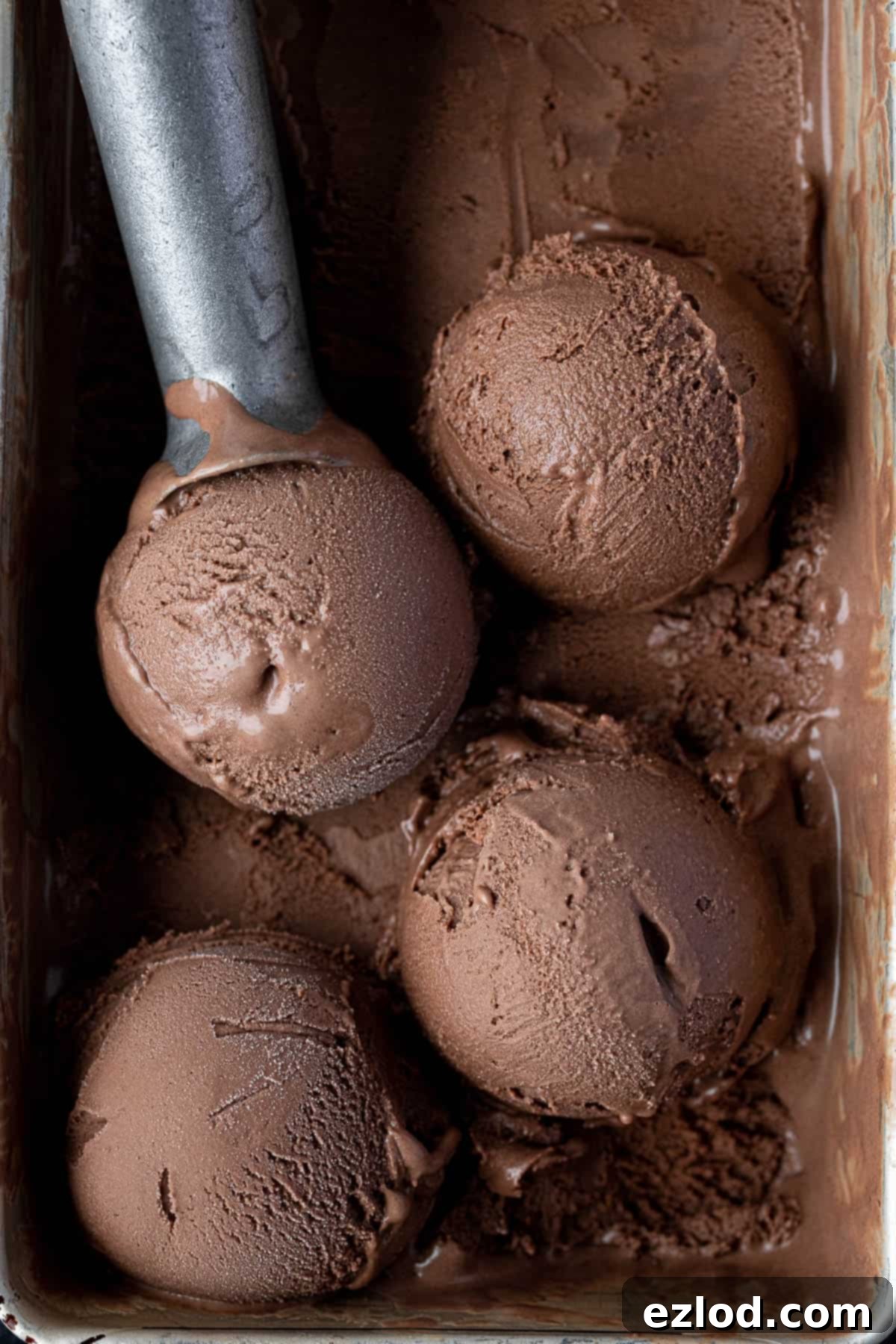 Close up view of several perfectly scooped portions of vegan malted chocolate ice cream in a bowl, highlighting its smooth texture and inviting appeal.