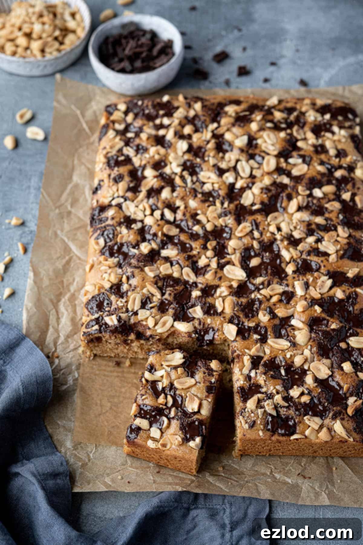 A beautifully sliced vegan peanut butter cake, with one slice removed to reveal the fluffy interior and delicious toppings.