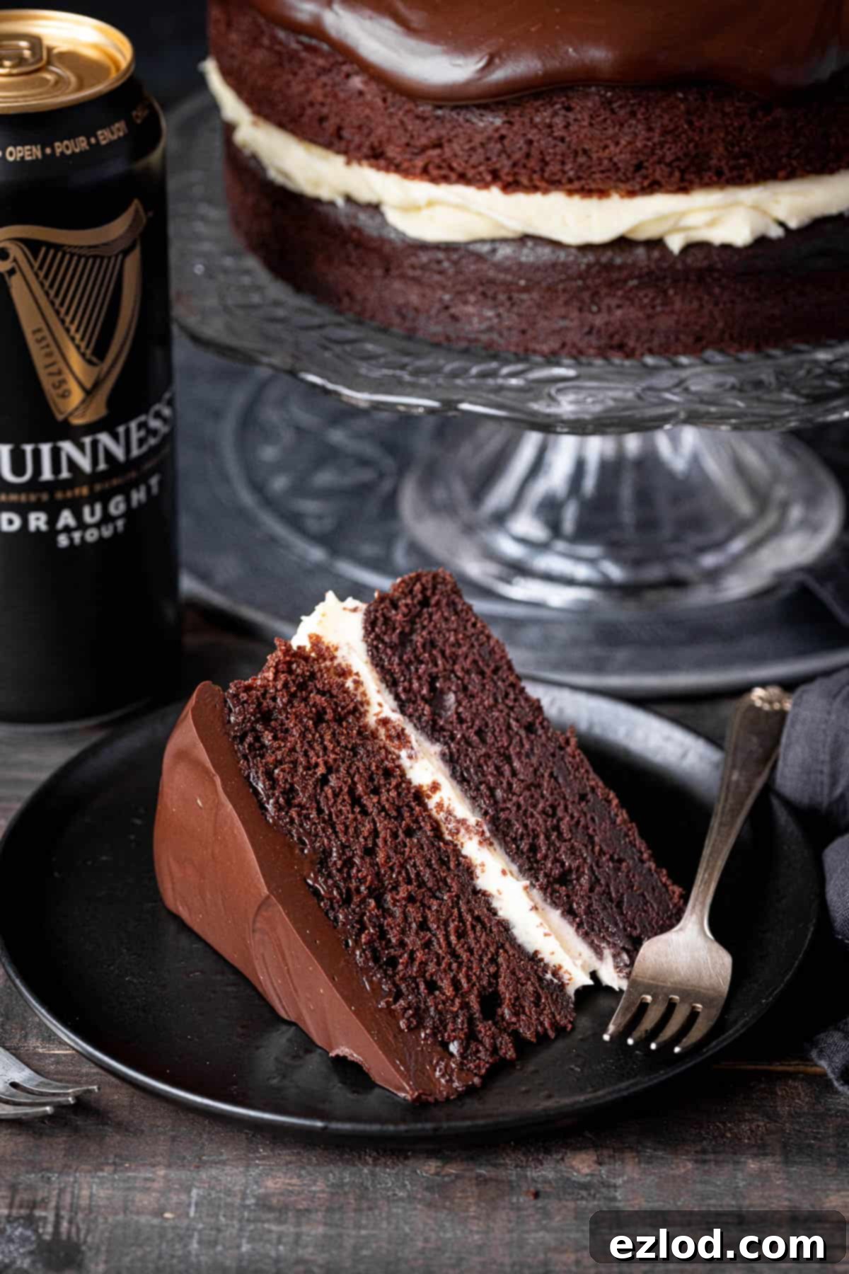 A slice of vegan Guinness chocolate cake on a black plate with a can of Guinness.