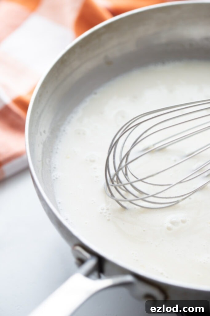 Whisking flour into butter and garlic to create a roux.