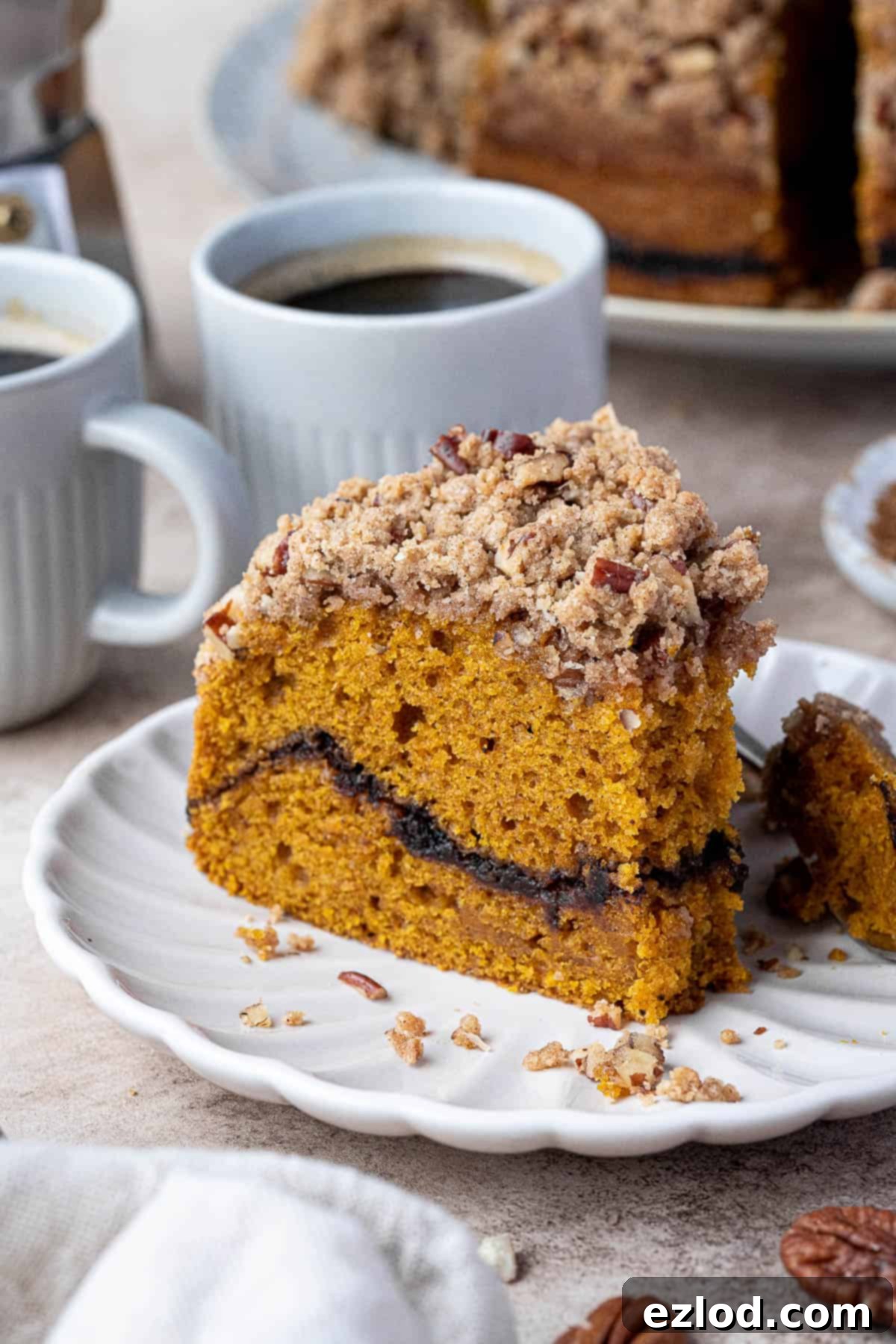 A close-up of a slice of vegan pumpkin coffee cake with a fork taking a bite, showcasing the moist texture and the cinnamon sugar layer.
