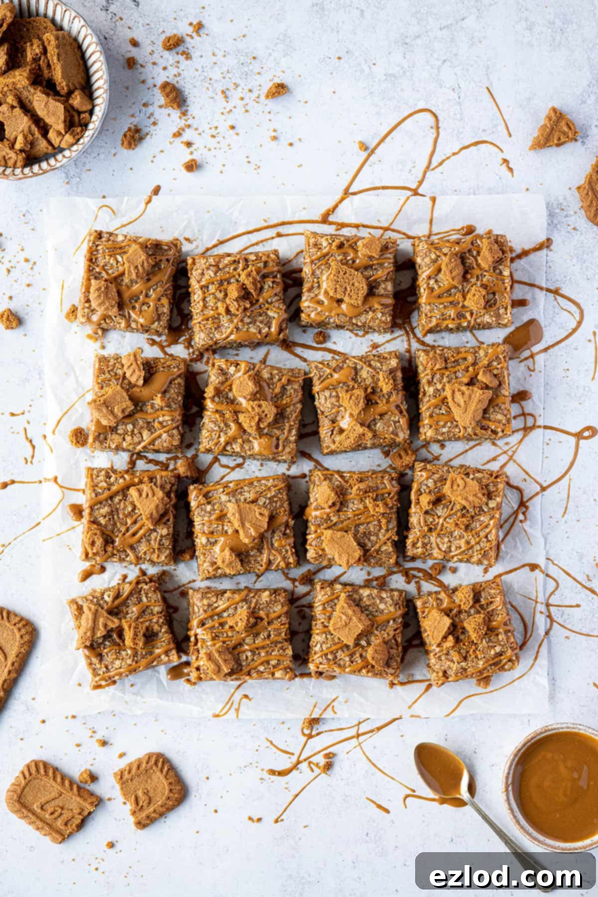 Vegan Biscoff flapjacks with bowls of Biscoff and Biscoff cookies. A close-up shot showcasing their golden-brown, chewy texture.