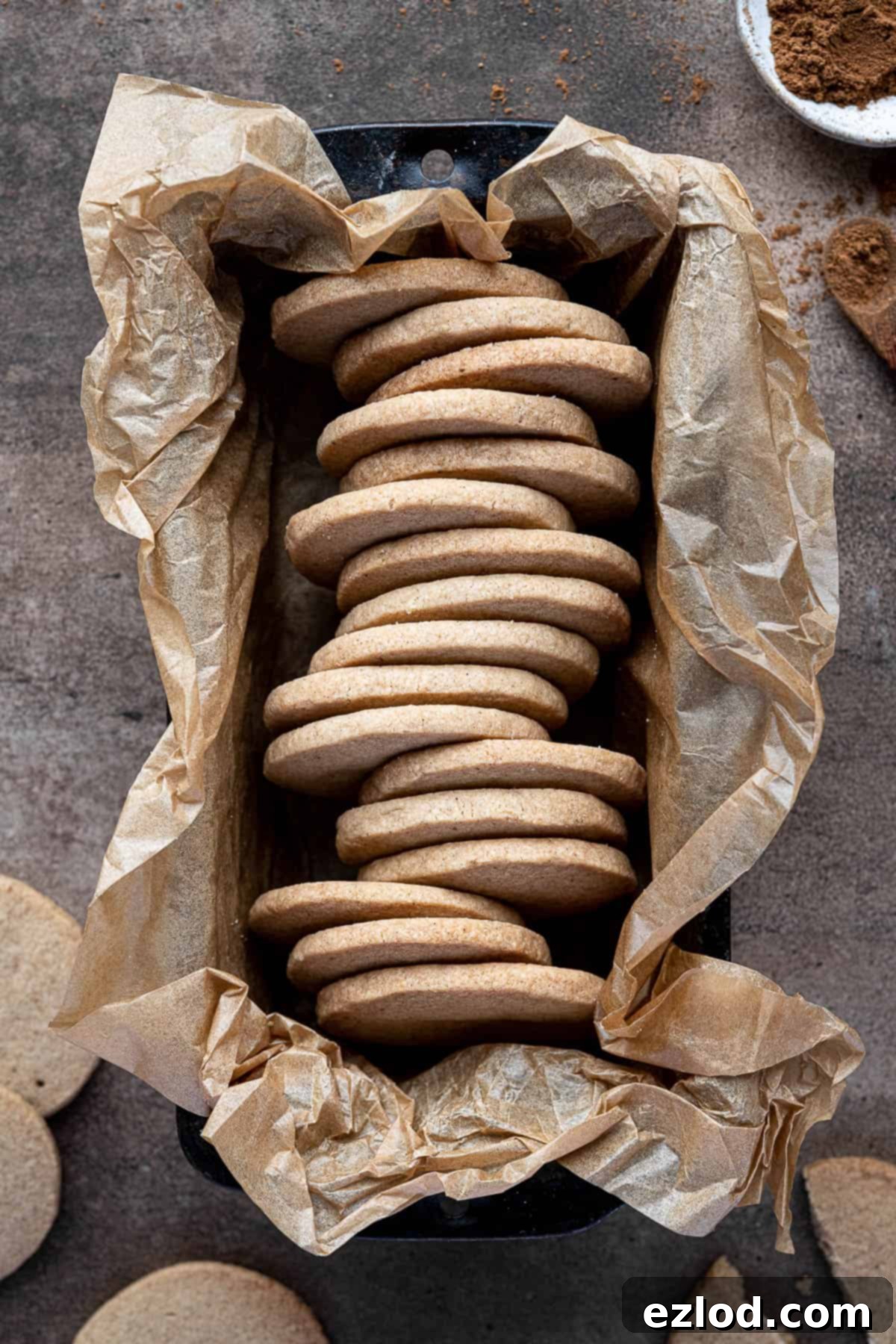 Autumn Plant Based Pumpkin Spice Shortbread 2 Vegan pumpkin spice shortbread cookies in a baking parchment lined loaf tin, showcasing their golden-brown edges and inviting texture.