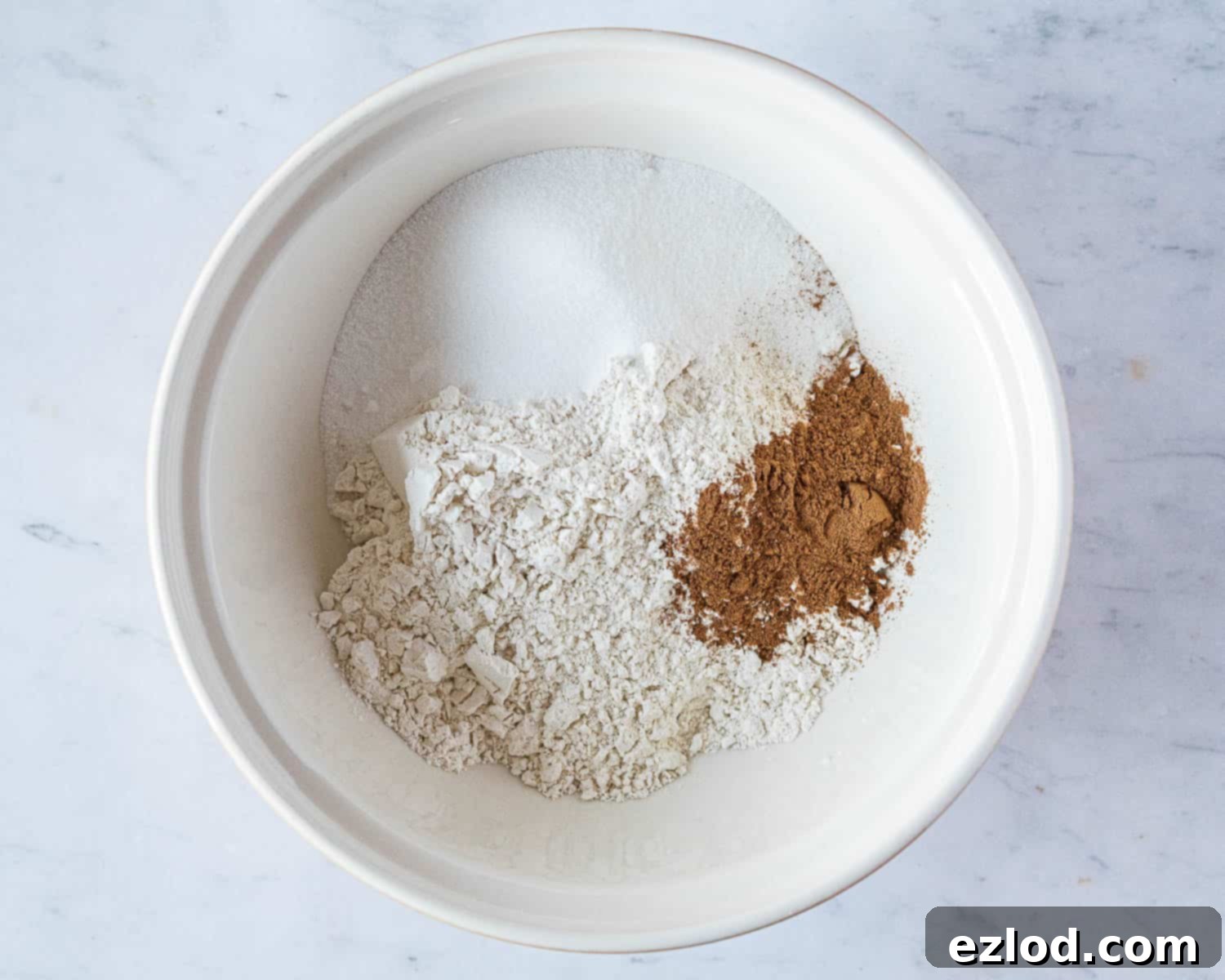 Step 1: Dry ingredients (flour, pumpkin spice, sugar) mixed together in a large white bowl.