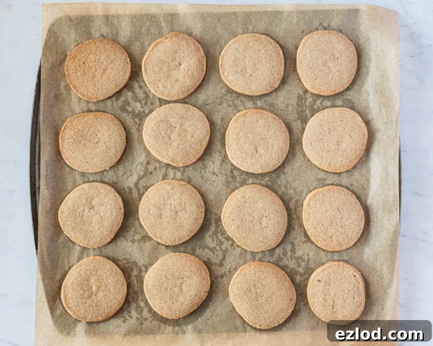 Step 7: Baked pumpkin spice shortbread cookies cooling on a baking tray, showing their golden edges.