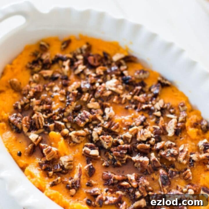 Close-up of a healthy sweet potato and butternut squash casserole mash, garnished with pecans.
