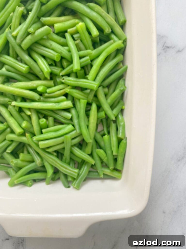 Wholesome Gluten Free Green Bean Casserole 4 Overhead image: freshly cut and trimmed green beans in a white casserole dish, ready for preparation.