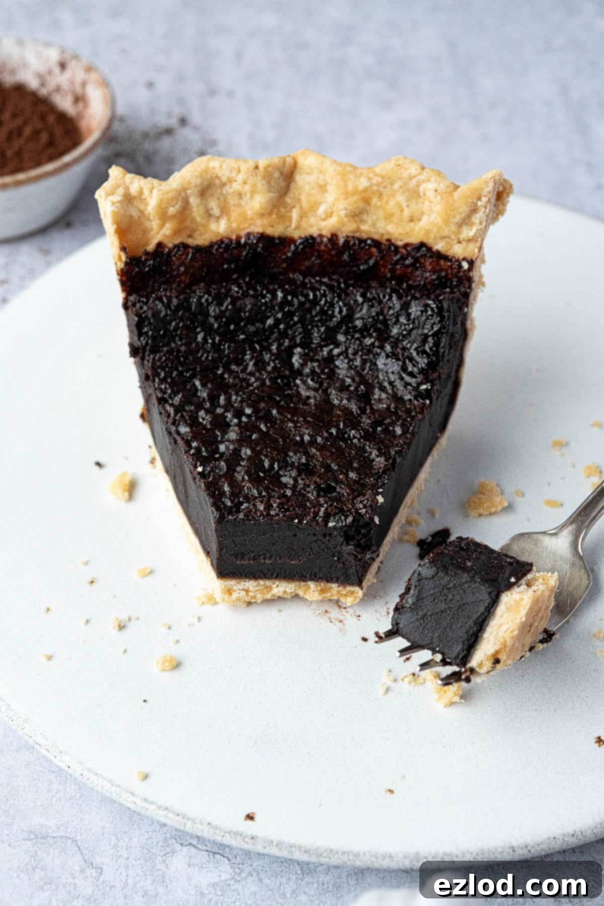 A close-up shot of a slice of vegan chocolate chess pie with a forkful removed, showing the luscious filling.