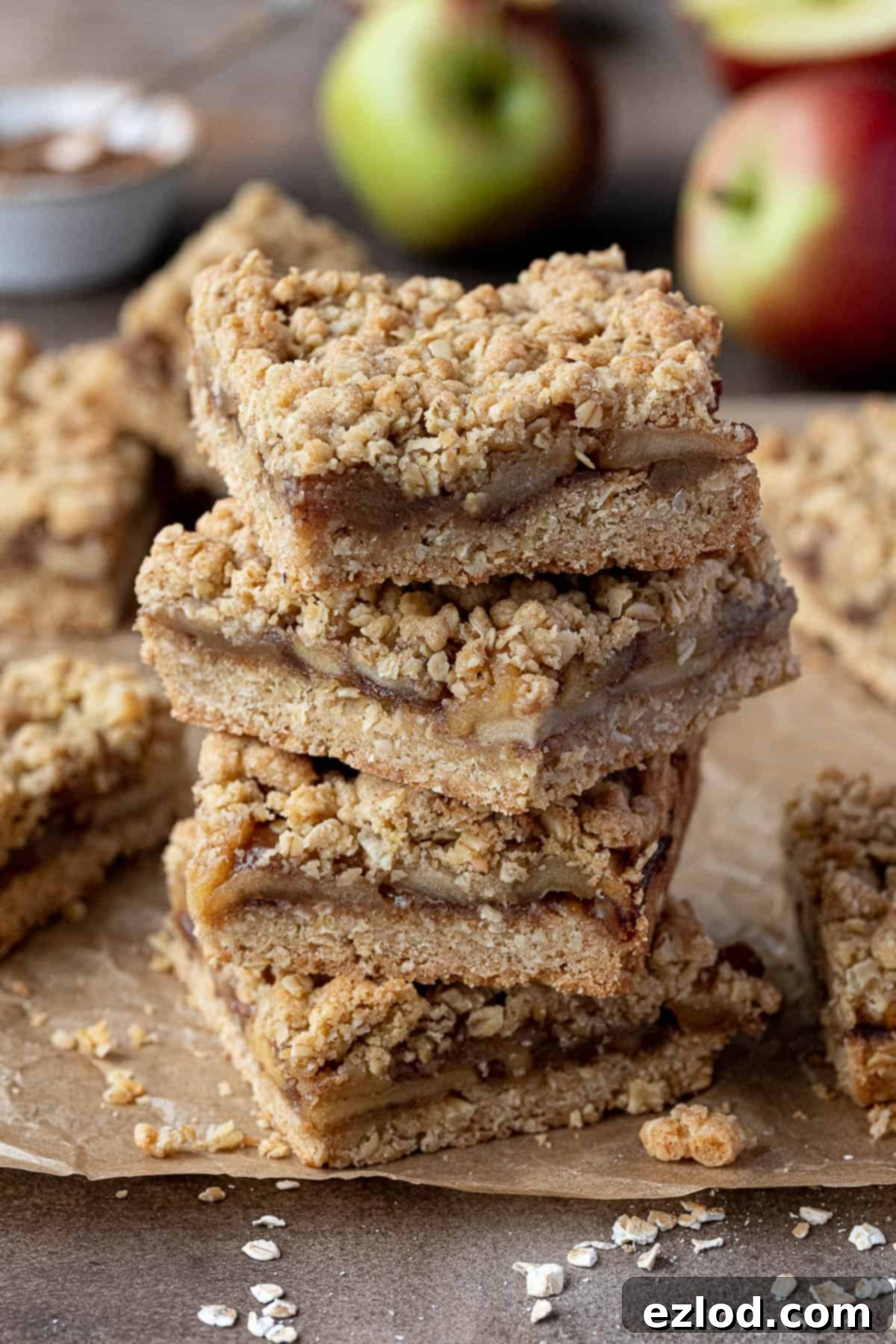 A stack of golden brown vegan apple crumble bars, showing the crumbly topping and apple filling.