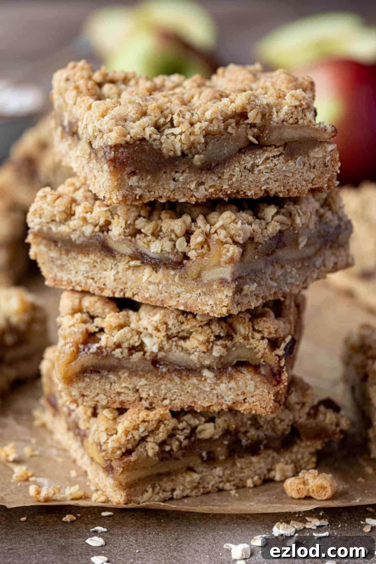 Close-up of a stack of golden brown vegan apple crumble bars, showing the textured topping and layers.
