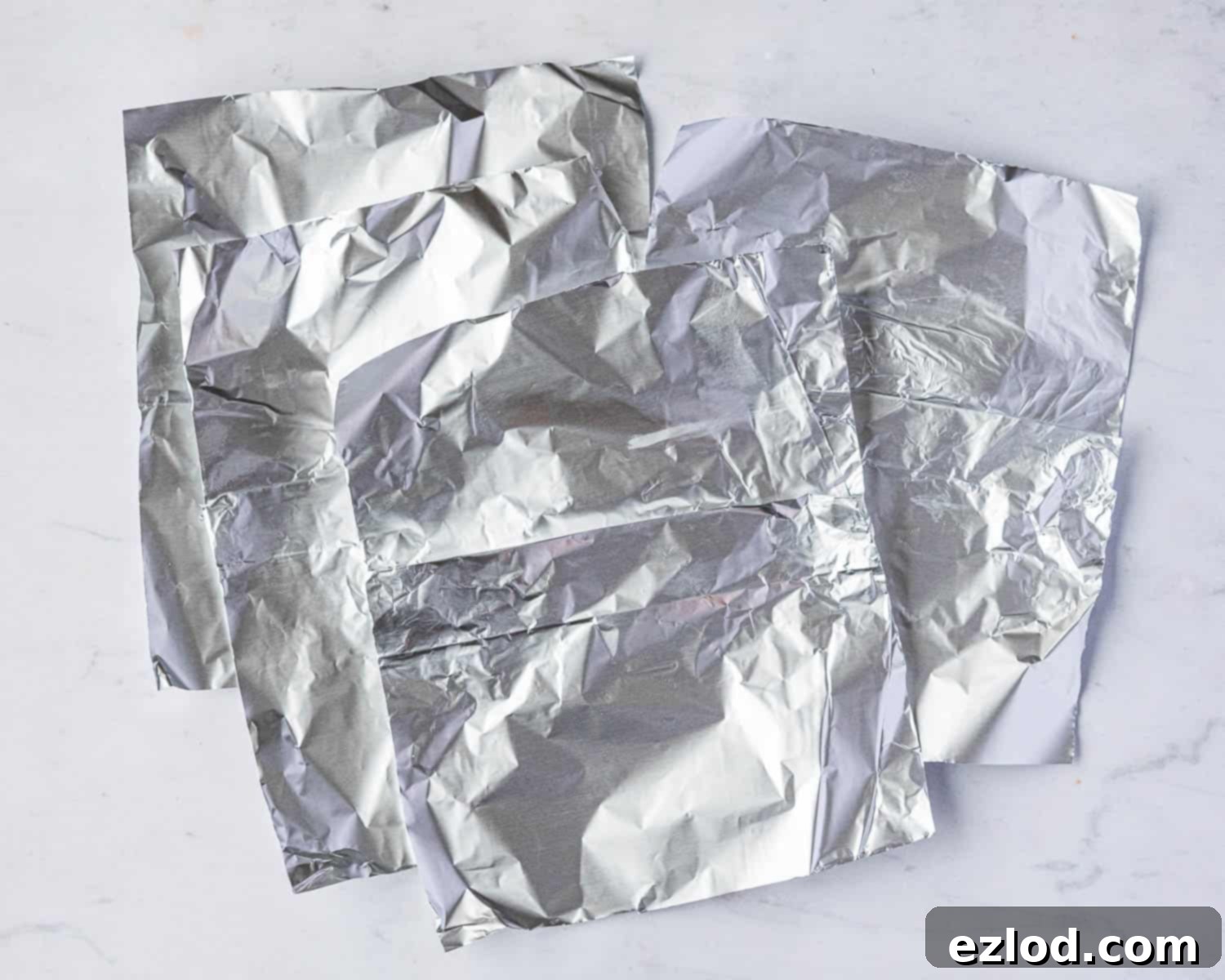 A prepared piece of tin foil with a pleat in the center, ready to cover a pudding bowl.