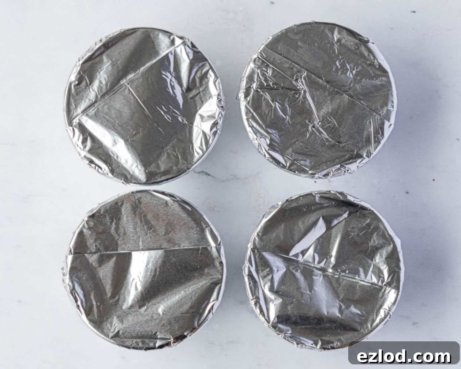 Individual pudding bowls with berry compote and sponge batter, securely covered with pleated tin foil.