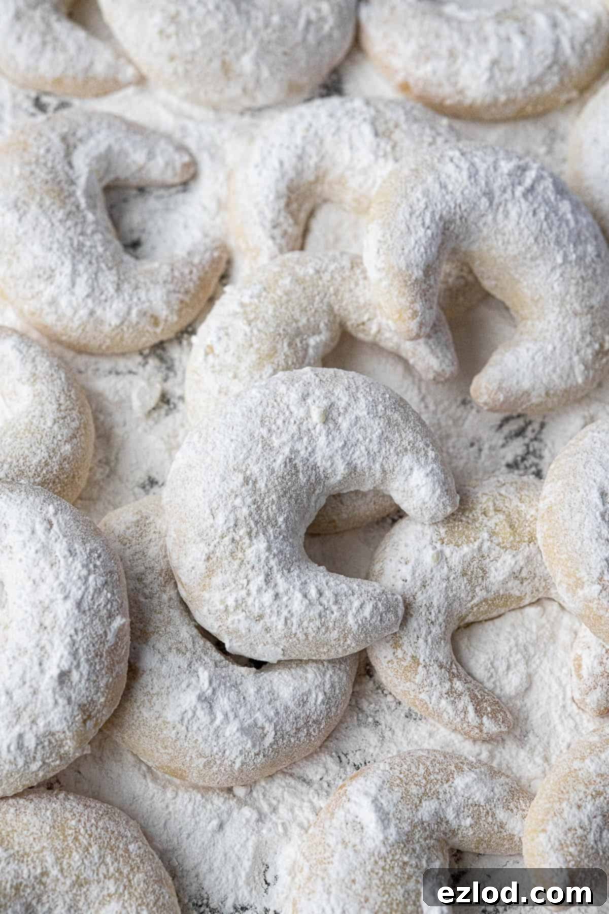 A close-up shot showcasing the delicate texture and snowy coating of several Vegan Vanillekipferl cookies.