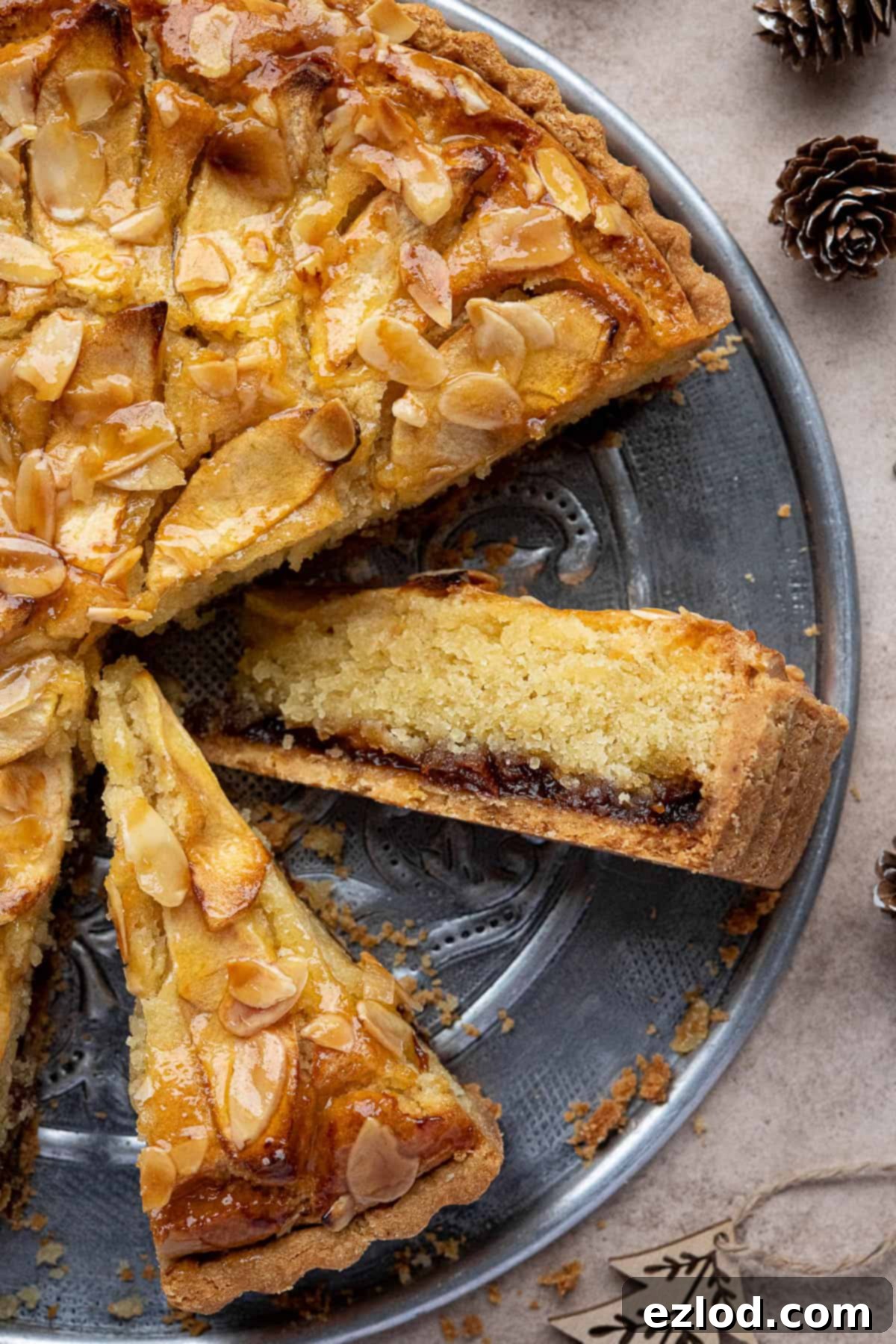 A close-up view of a slice of the vegan mincemeat frangipane tart, showcasing its layers of crisp pastry, fruity mincemeat, and creamy frangipane with a hint of apple topping.