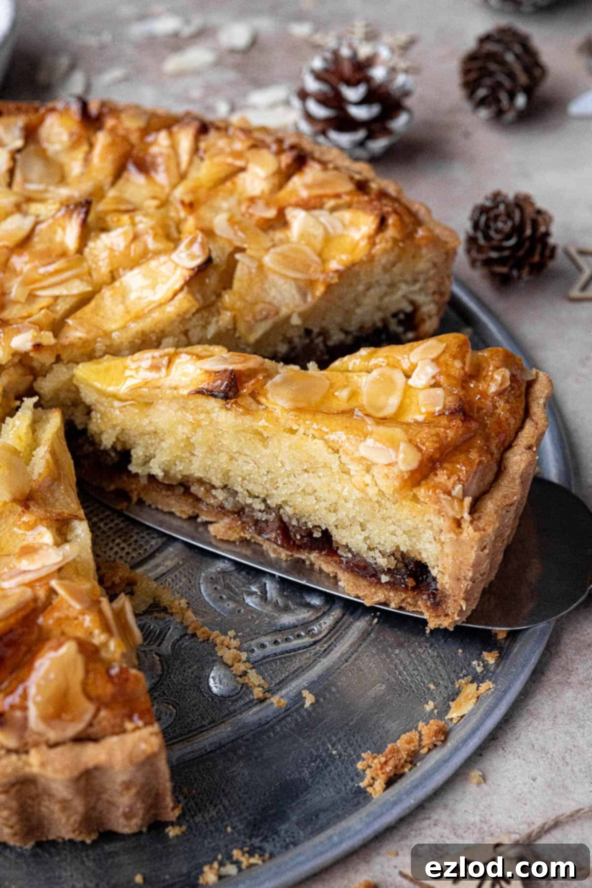 A close-up view of a single slice of baked vegan frangipane tart, displaying the layers of pastry, mincemeat, and almond frangipane, with a hint of golden crust.
