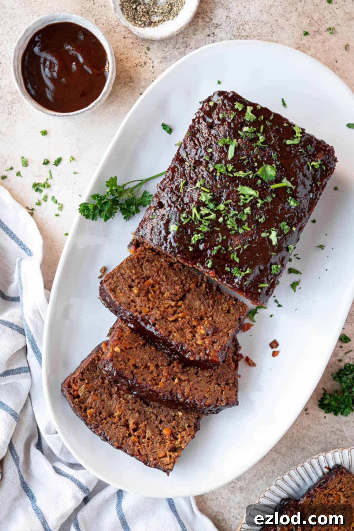 A beautiful vegan seitan meatloaf, glazed with barbecue sauce, presented on a white plate.