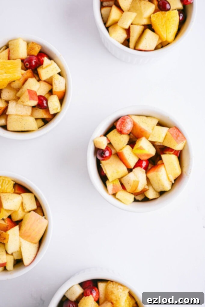 Overhead shot of four white ramekins with diced up fruit for a holiday crisp recipe