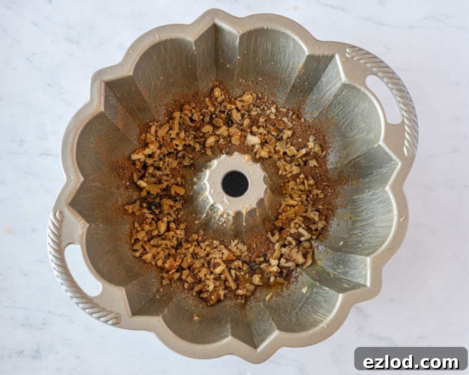 Step 6, the prepared bundt tin with butter, sugar, and nuts at the bottom.