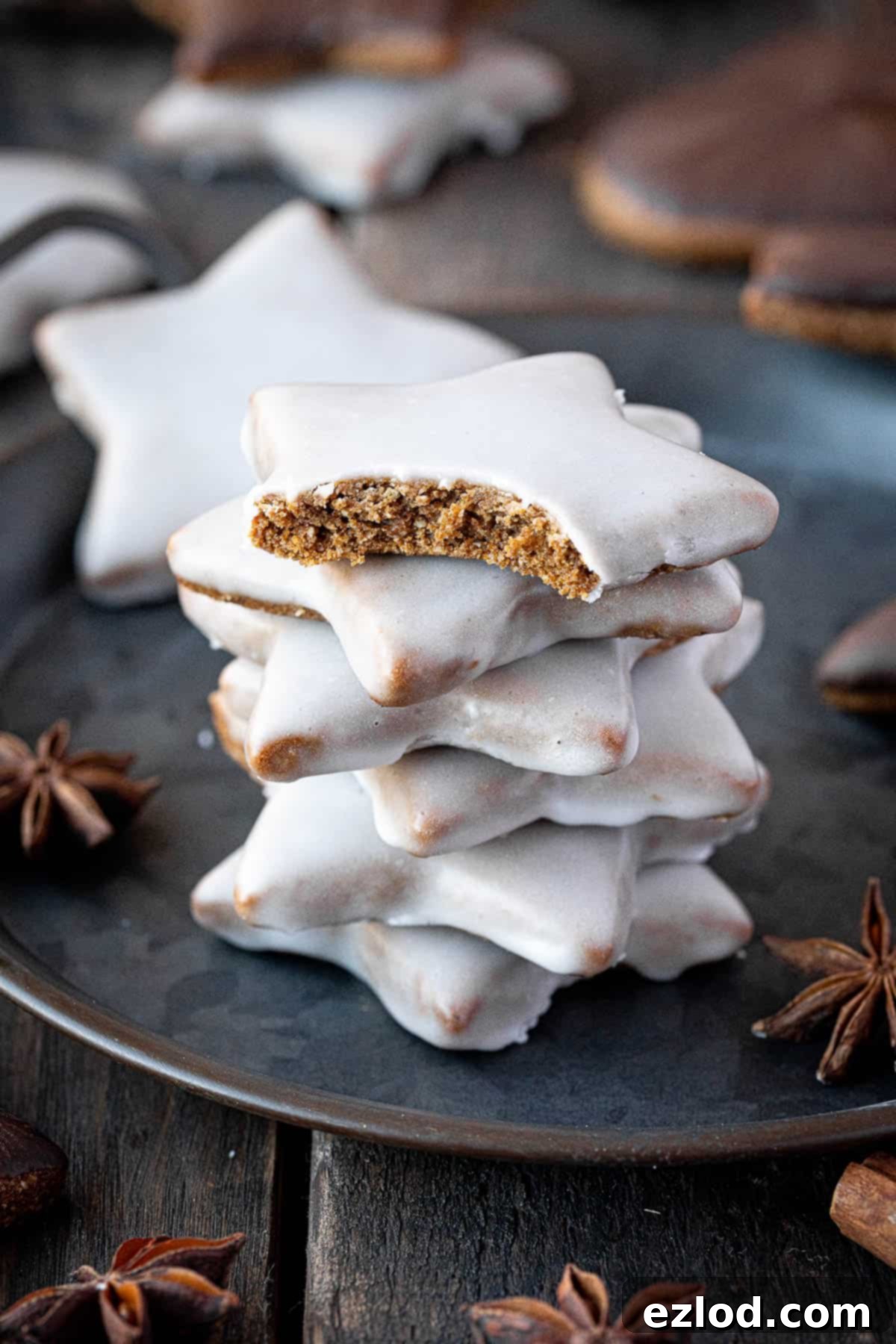 A stack of glazed vegan lebkuchen stars, one with a bite taken out of it, showcasing its soft interior.