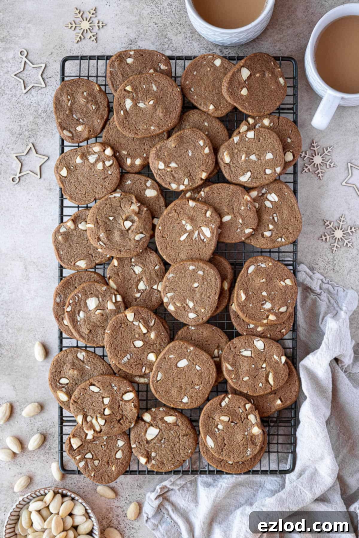 Freshly baked vegan brunkager cooling on a wire rack, surrounded by festive decorations, a bowl of almonds, and cups of tea, creating a cozy holiday ambiance.