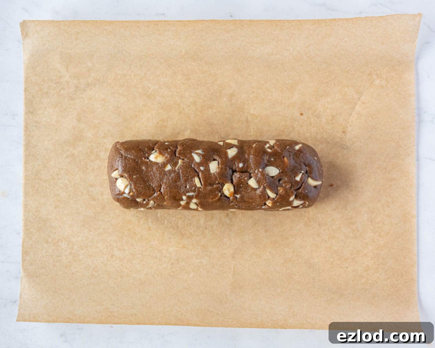 Step 5 in making vegan brunkager: the warm dough has been shaped into a neat log on a piece of baking parchment.