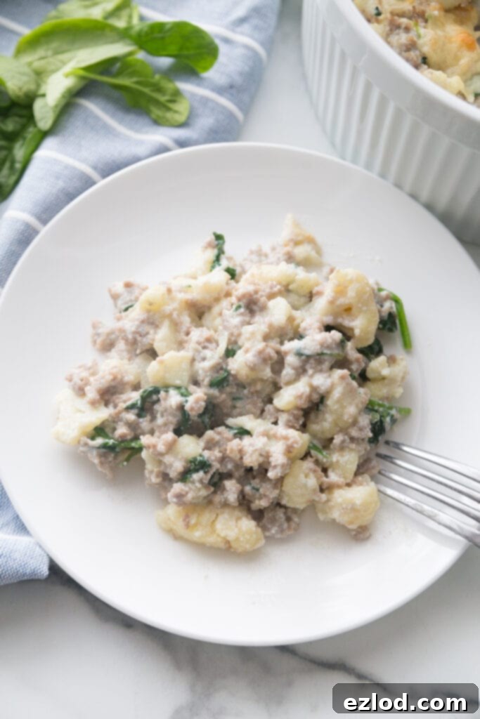 A serving of healthy sausage and cauliflower casserole on a white ceramic plate, showcasing the rich texture and delicious ingredients like ricotta and Parmesan cheese.