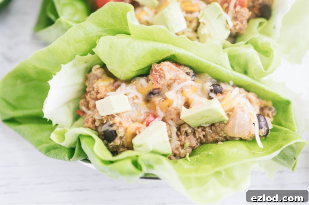 Close up photo of crock pot taco casserole in a lettuce wrap and topped with avocado.