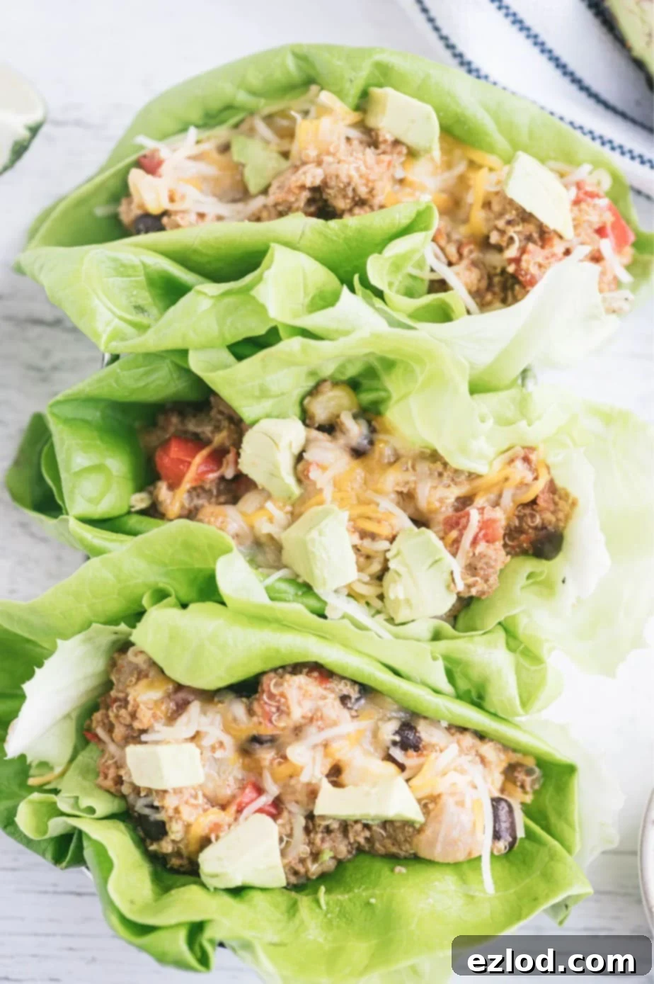 Close up photo of lettuce wraps filled with Mexican crock pot casserole topped with avocado.