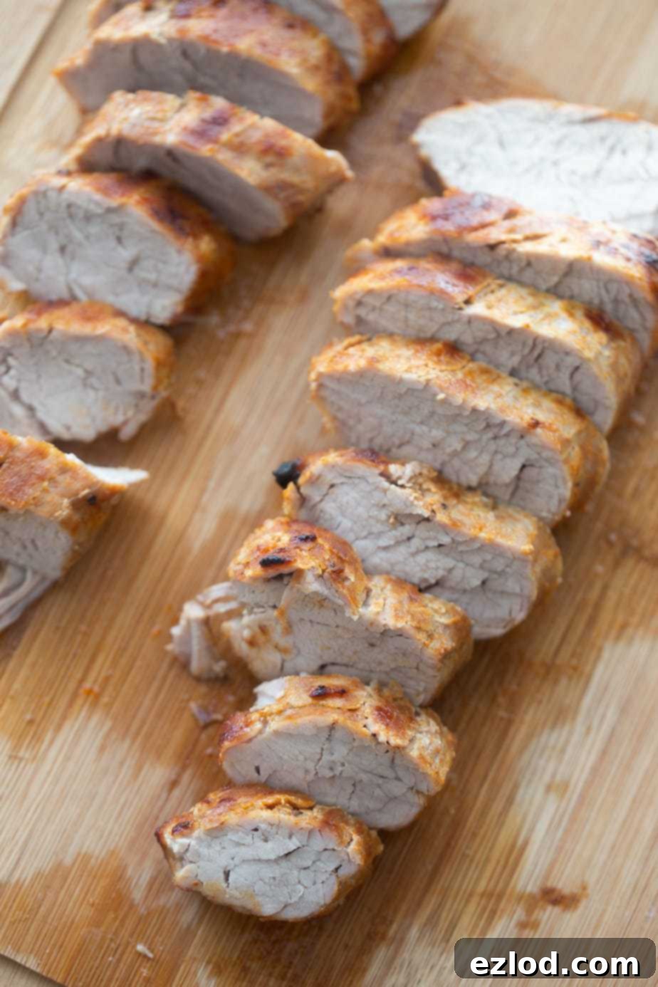 Two sliced Air Fryer pork tenderloins on a wooden cutting board.