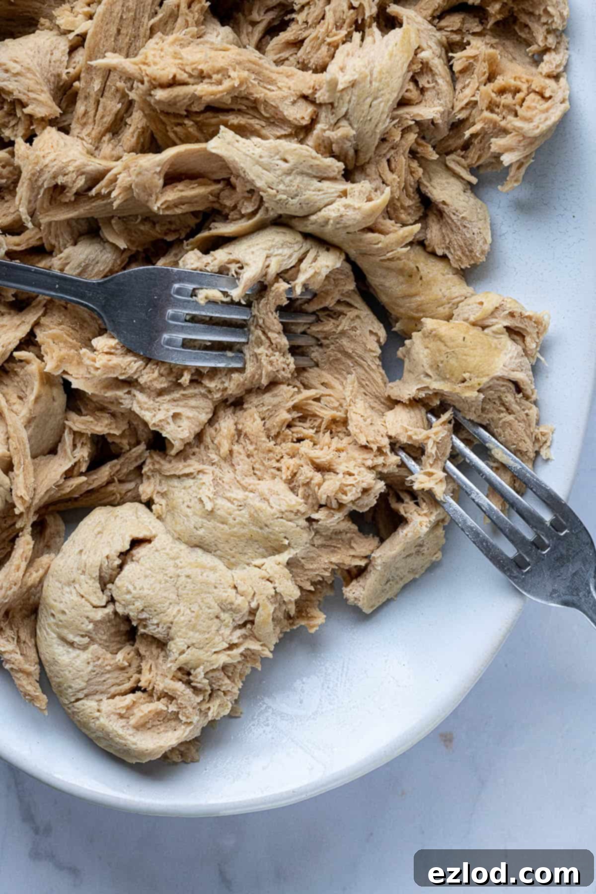 The seitan being shredded with two forks.