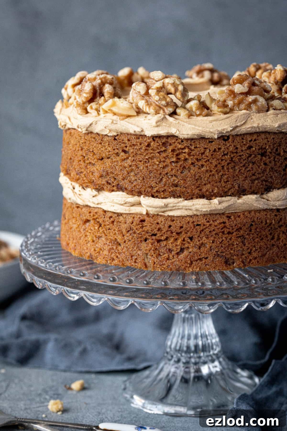 Close-up of a perfectly frosted gluten-free vegan coffee and walnut cake, adorned with walnuts.