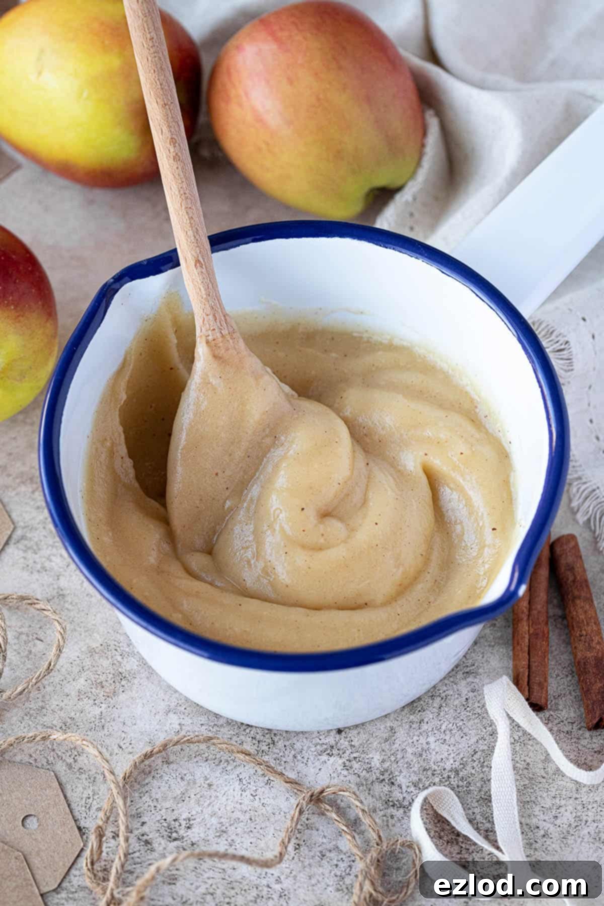 Vegan apple curd gently simmering in an enamel pan, looking smooth and ready to thicken.